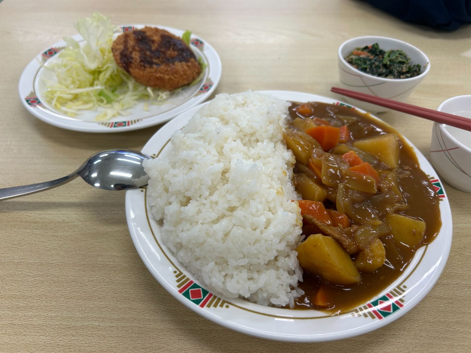 寮食の一例。カレーライス、コロッケとサラダ、小鉢