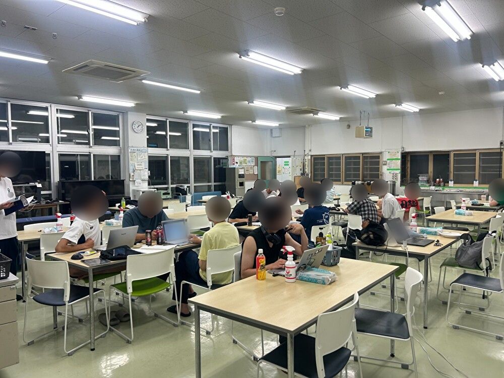 夜の寮食堂。寮生がノートパソコンを広げて勉強している様子