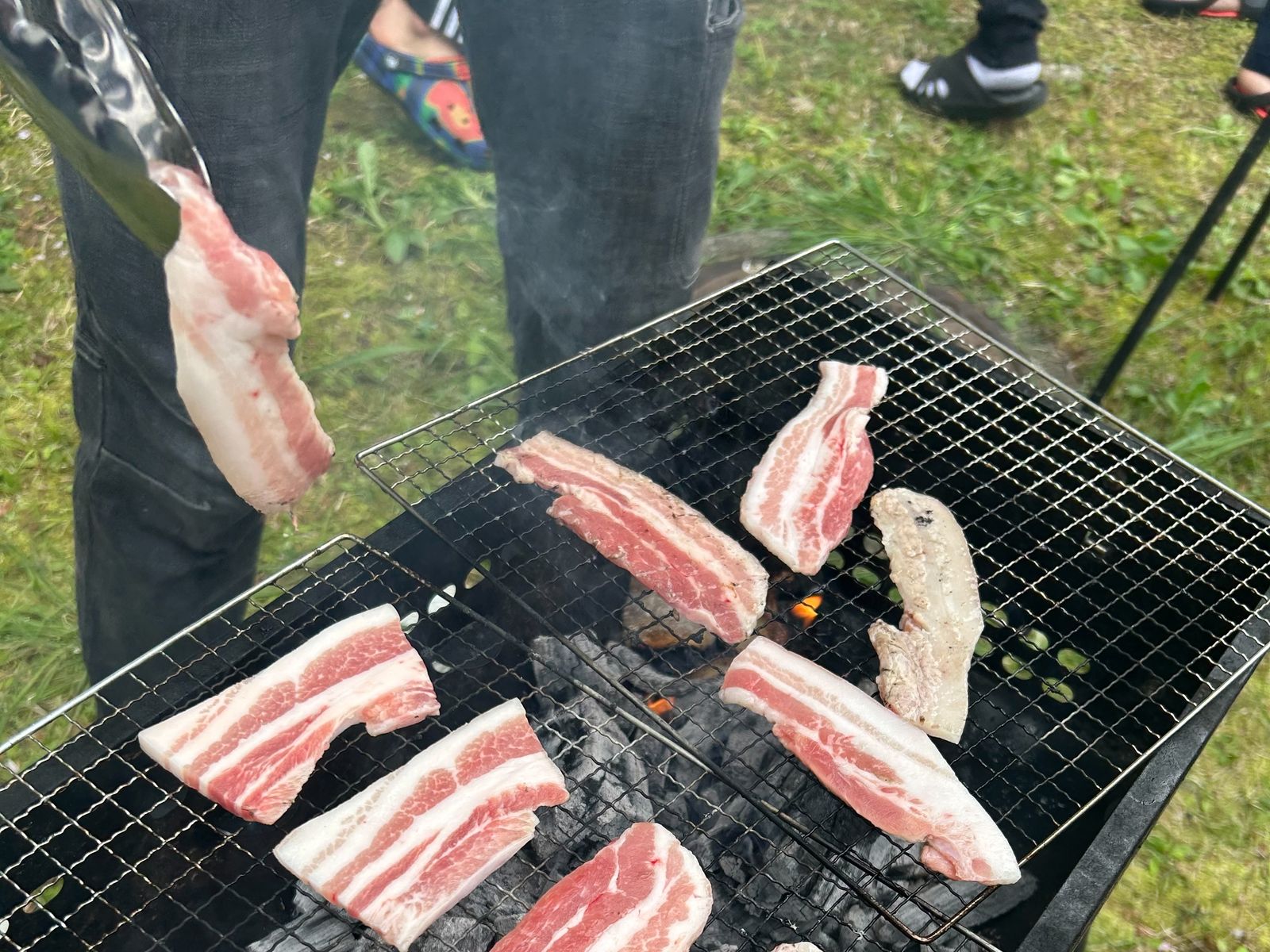中庭で行う新歓BBQ。炭火の網の上で焼かれる肉