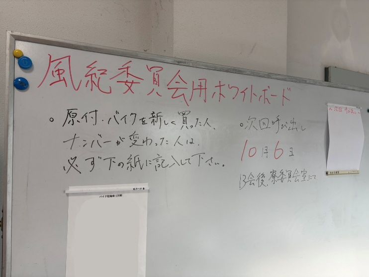 風紀委員会用のホワイトボード。原付・バイクの登録に関する連絡と次回呼び出し日が書かれている